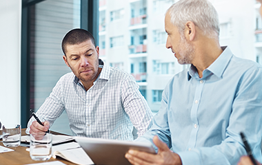 Two professionals reviewing documents together during a meeting.