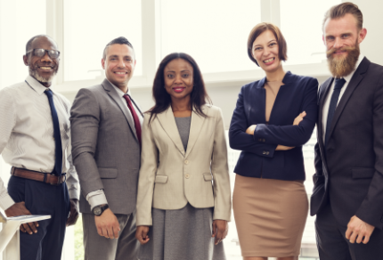 Five people in business attire standing in line smiling at the camera.