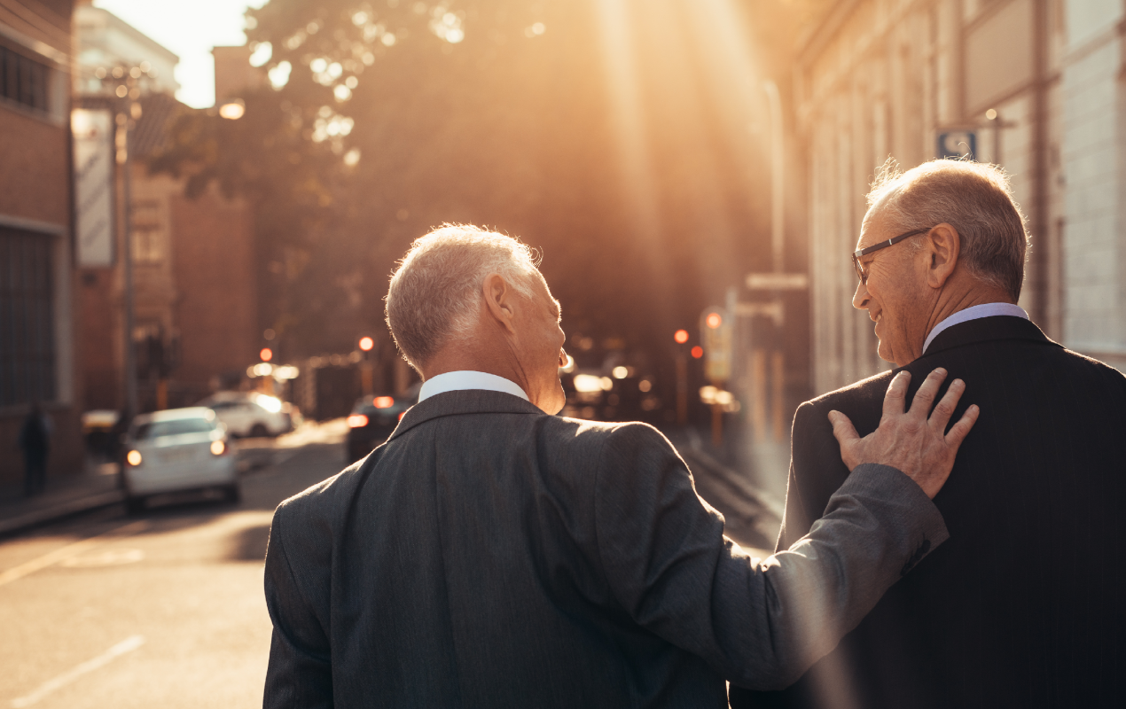 Rear view of two business people walking outdoors and talking on a sunny day.