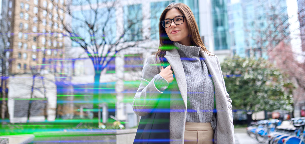 A young professional walking outdoors in an urban park setting.