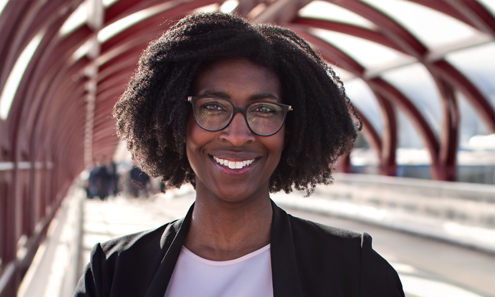 A young professional walking outdoors in an urban park setting.